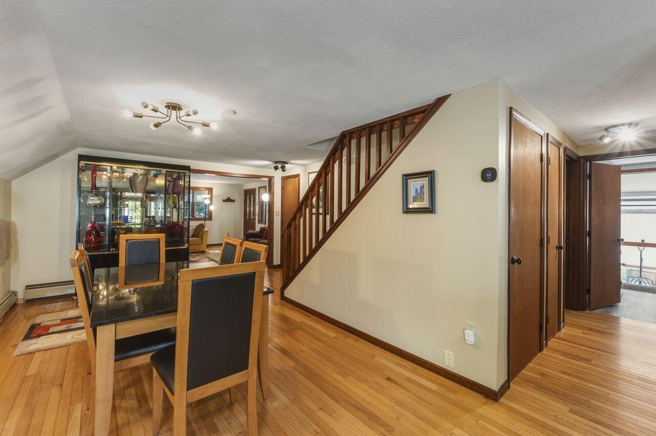 Dining room with hardwood floors, a glass-front cabinet, and a wooden staircase.