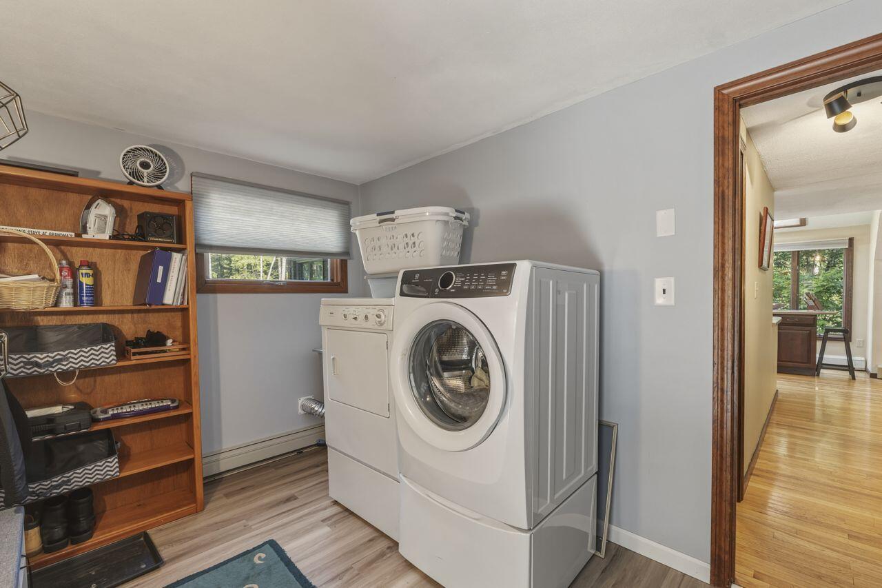 Laundry room with front-loading washer and dryer beside wooden storage shelves.