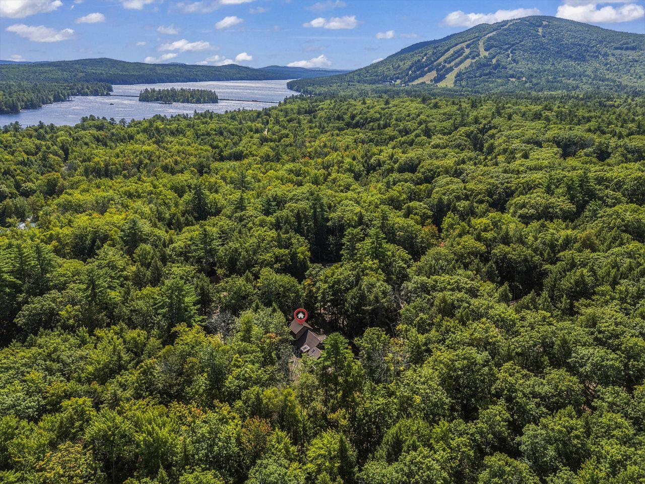 Aerial view of a forested home, lake, and mountain near Bridgton, Maine.