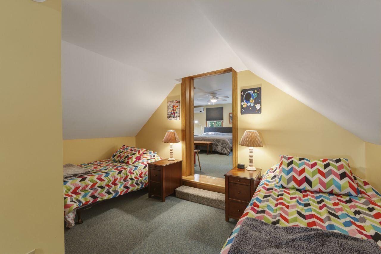 Attic bedroom with two colorful chevron-covered beds and a large mirror between them.