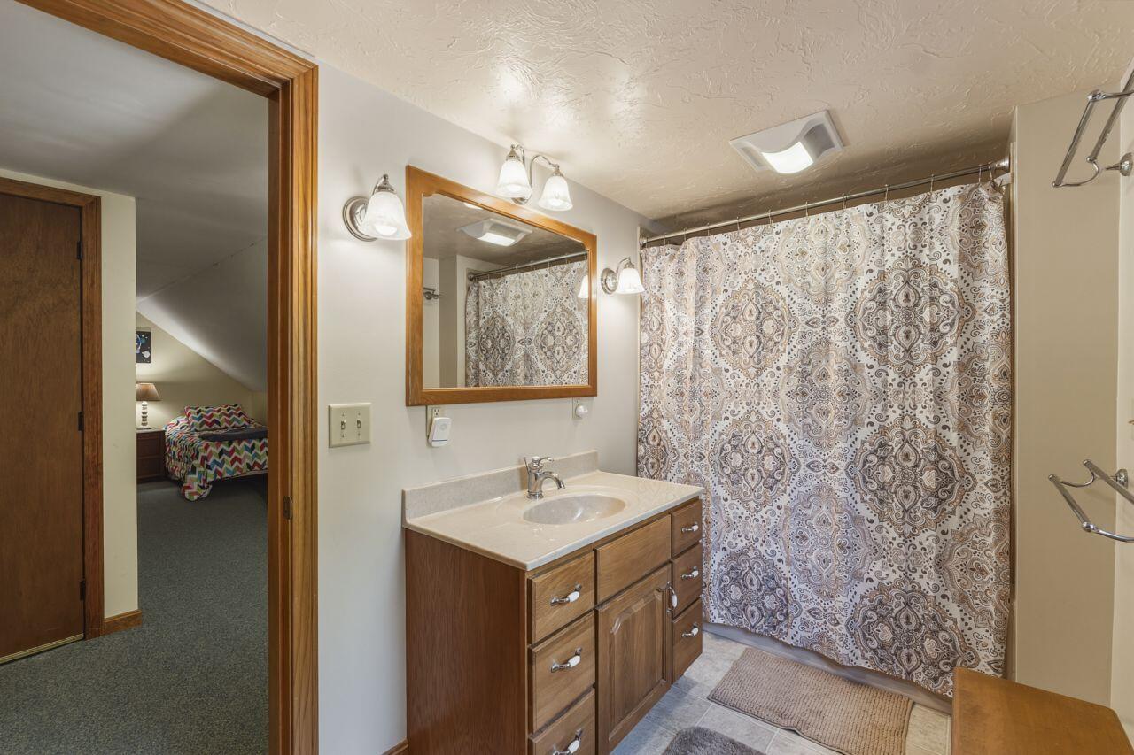 Bathroom with a wood vanity, large mirror, and patterned shower curtain.