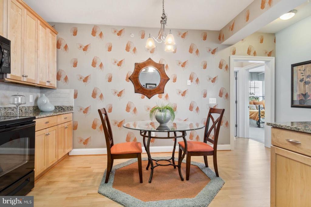 Dining area with a glass-top table, orange-cushioned chairs, and leaf-patterned wallpaper.