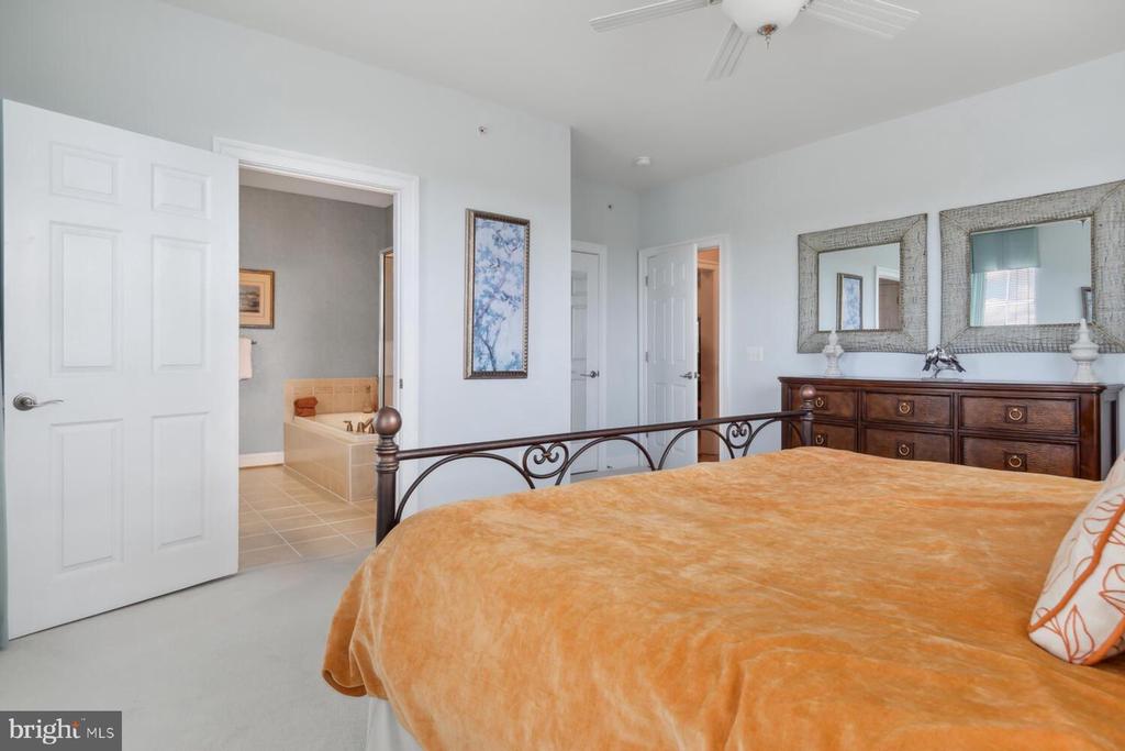 Bedroom with orange bedding, an ornate black metal bed frame, and a dresser with two mirrors.