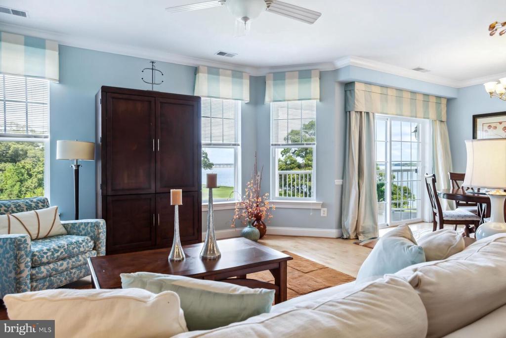 Furnished living room with blue walls, dark wood cabinet, and balcony doors overlooking the water.