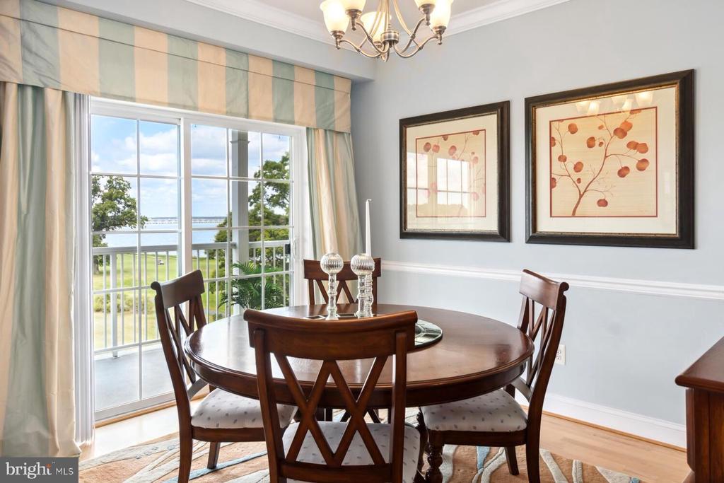Dining room with a round wooden table, chandelier, and sliding door overlooking the water.