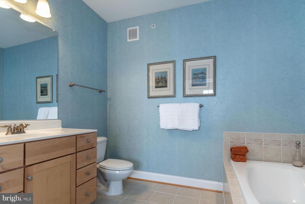 Bathroom with blue walls, a light wood vanity, and a built-in bathtub.
