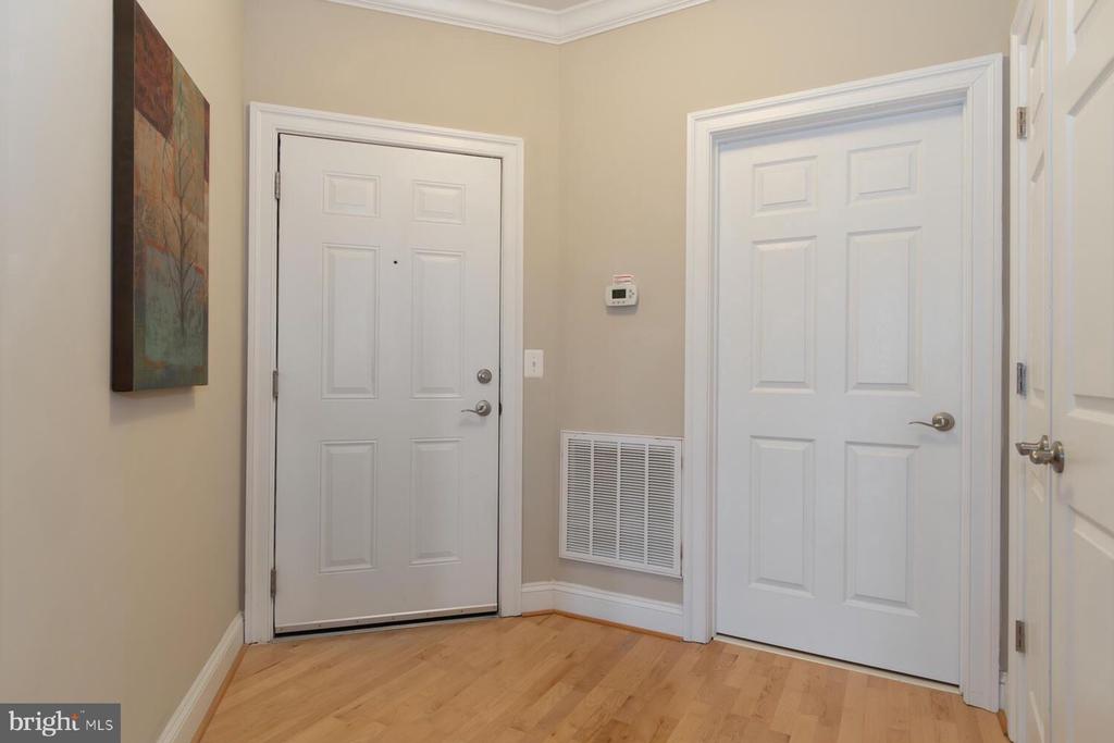 Entryway with light hardwood floors, three white paneled doors, and an air return vent.