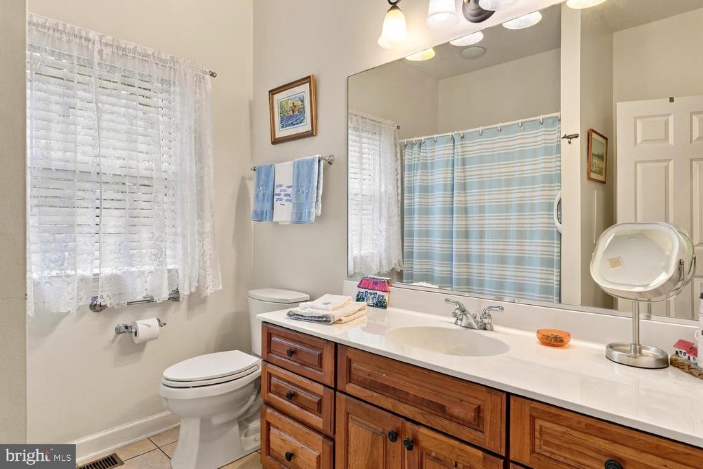 Bathroom with a wood vanity, white countertop, toilet, and blue-striped shower curtain.
