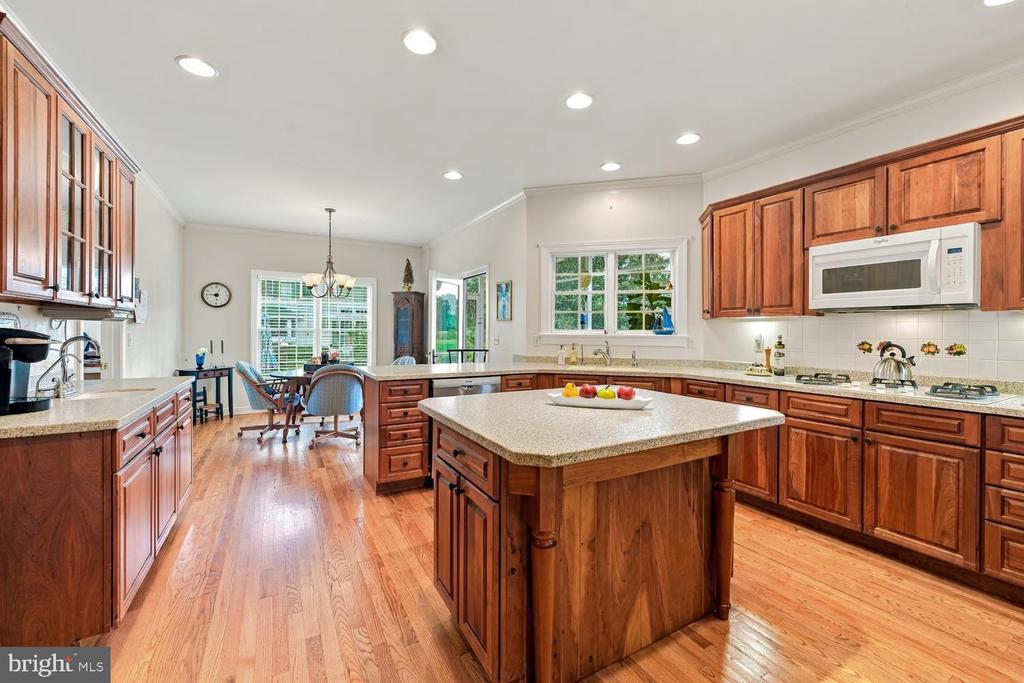 Kitchen with a large granite island, extensive wood cabinetry, and hardwood floors.