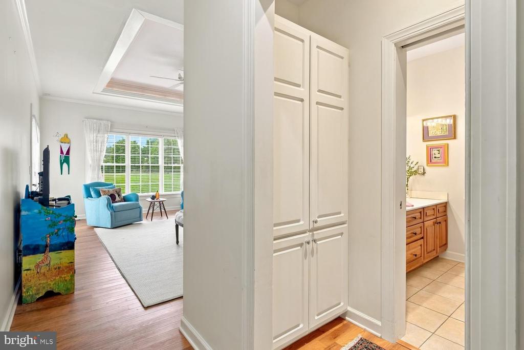 Hallway with built-in cabinets between a bright sitting room and a bathroom with a wood vanity.
