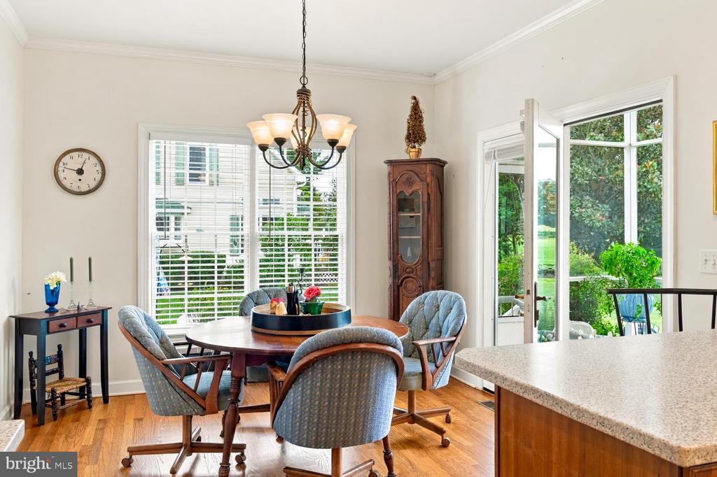 Dining room with a round wooden table, chandelier, and glass doors opening to a green garden.