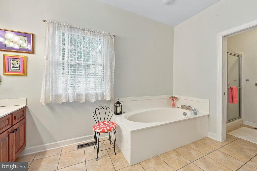 Bathroom with a large built-in soaking tub, tiled floor, and separate glass shower.