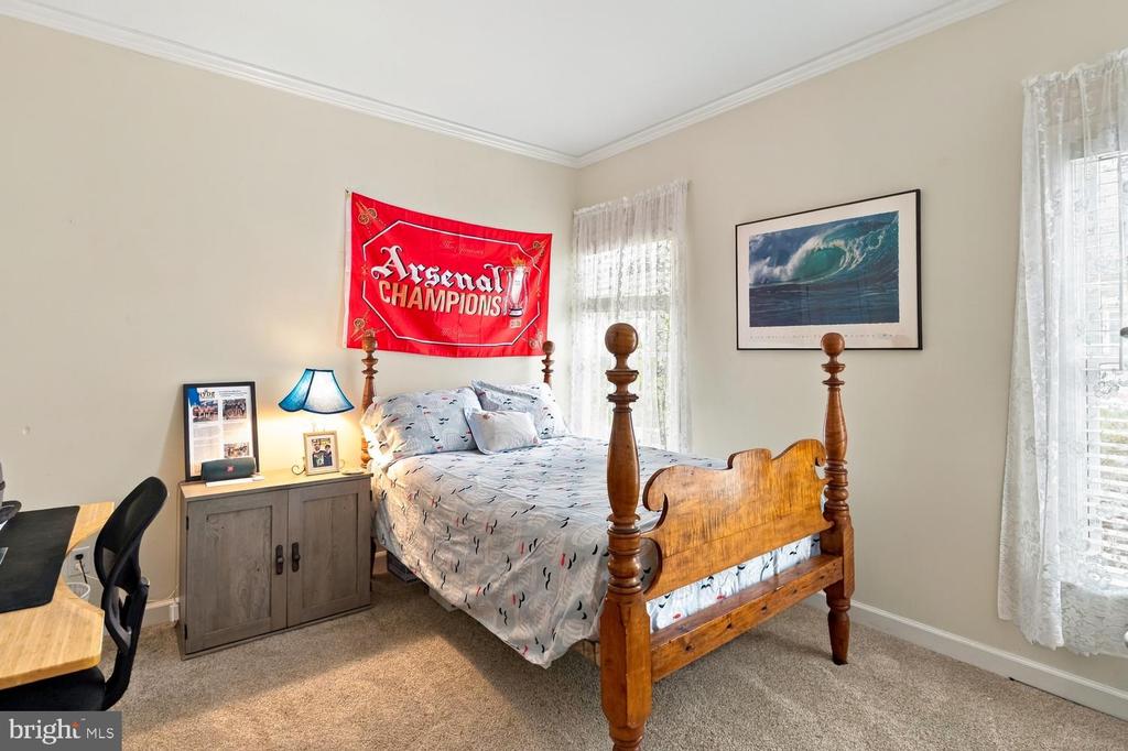 Bedroom with a wooden four-poster bed, Arsenal banner, and framed ocean-wave artwork.