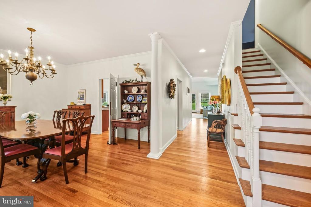 Dining room and entry hall with hardwood floors, a chandelier, and a white staircase with wood treads.