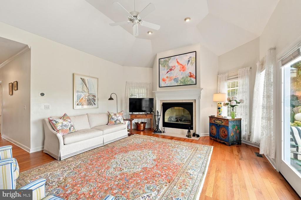Living room with vaulted ceiling, fireplace, white sofa, and ornate patterned rug.