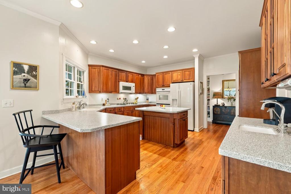 Kitchen with warm wood cabinets, granite counters, hardwood floors, and a central island.