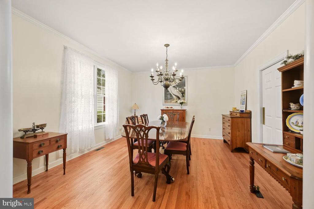 Dining room with a polished wooden table, chandelier, and hardwood floors.