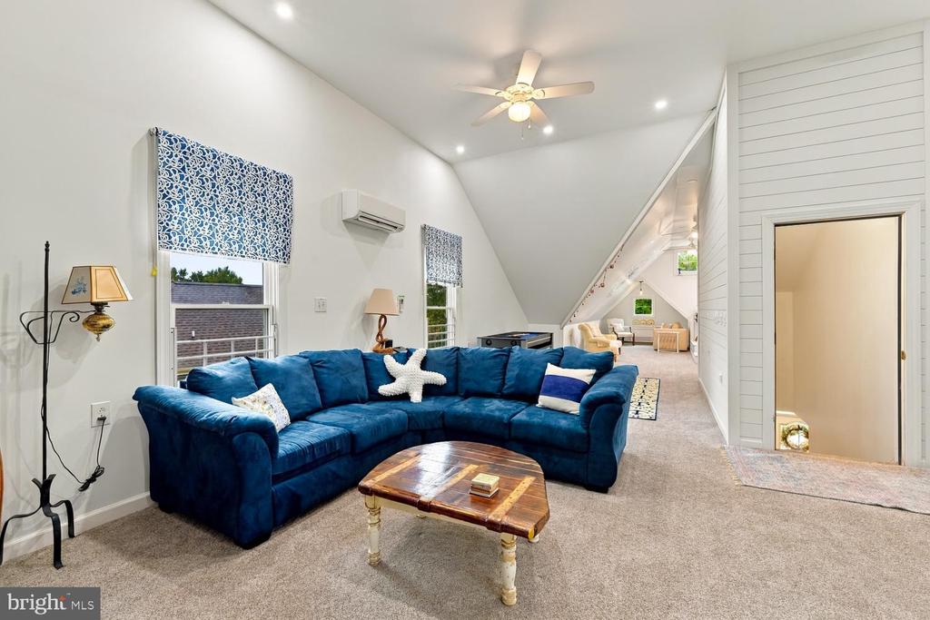 Living room with a blue sectional beneath a vaulted ceiling and a sitting area beyond.