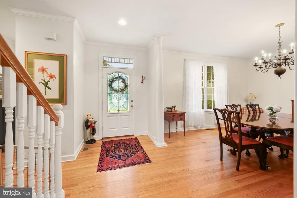 Foyer and dining area with hardwood floors, a stained-glass front door, and a staircase.