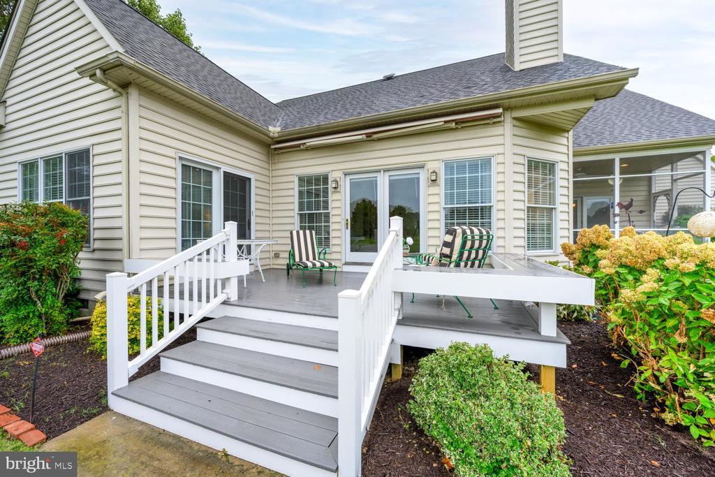 Raised gray deck with white railings and stairs, outdoor furniture, and a screened porch.
