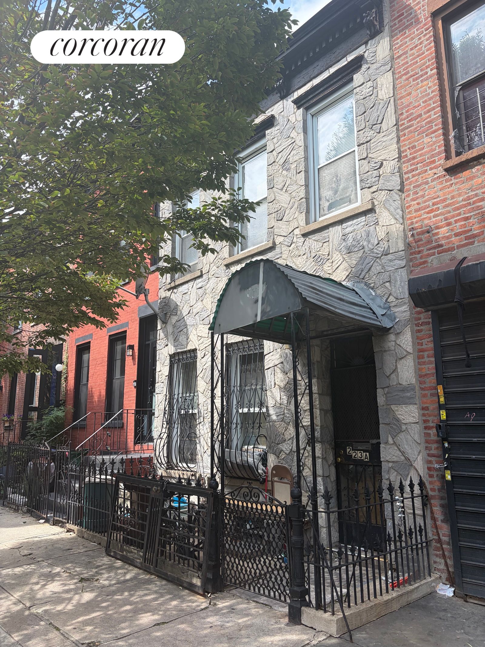 Brooklyn townhouse with a stone façade, metal entry awning, and iron fence.