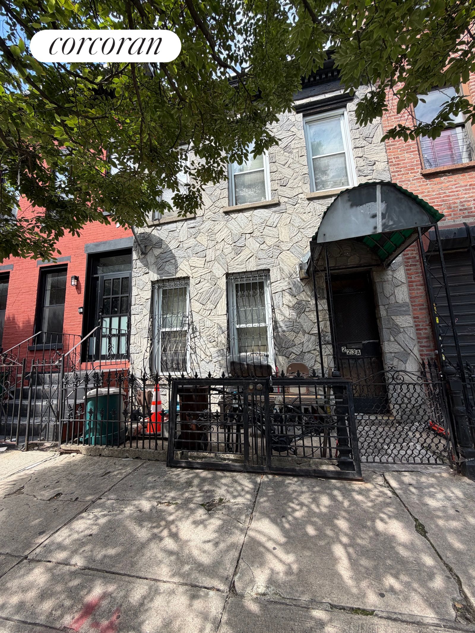 Stone-front townhouse with barred windows, iron railings, and a curved awning over the entrance.