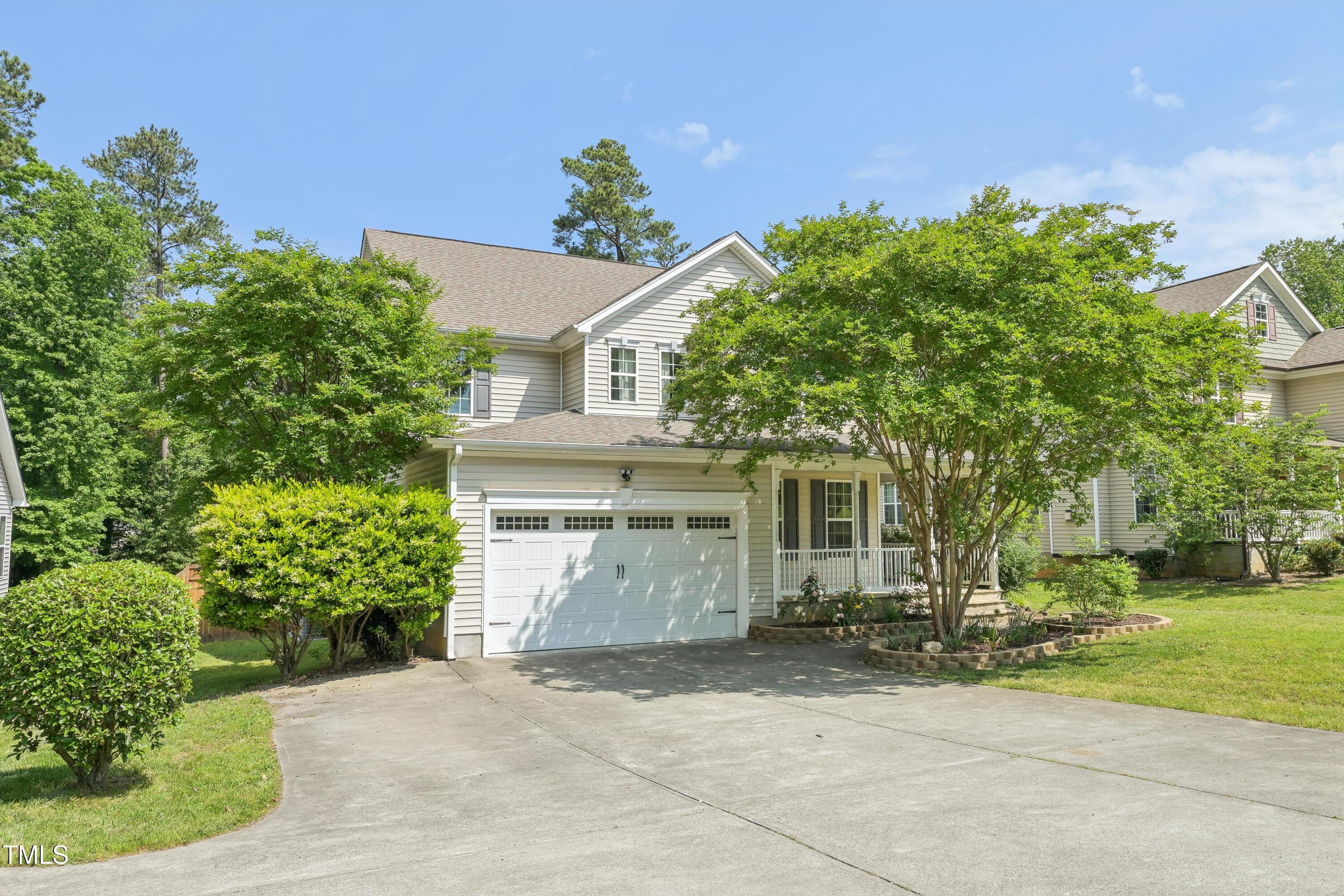 Two-story house with a double garage, covered porch, and leafy landscaping.