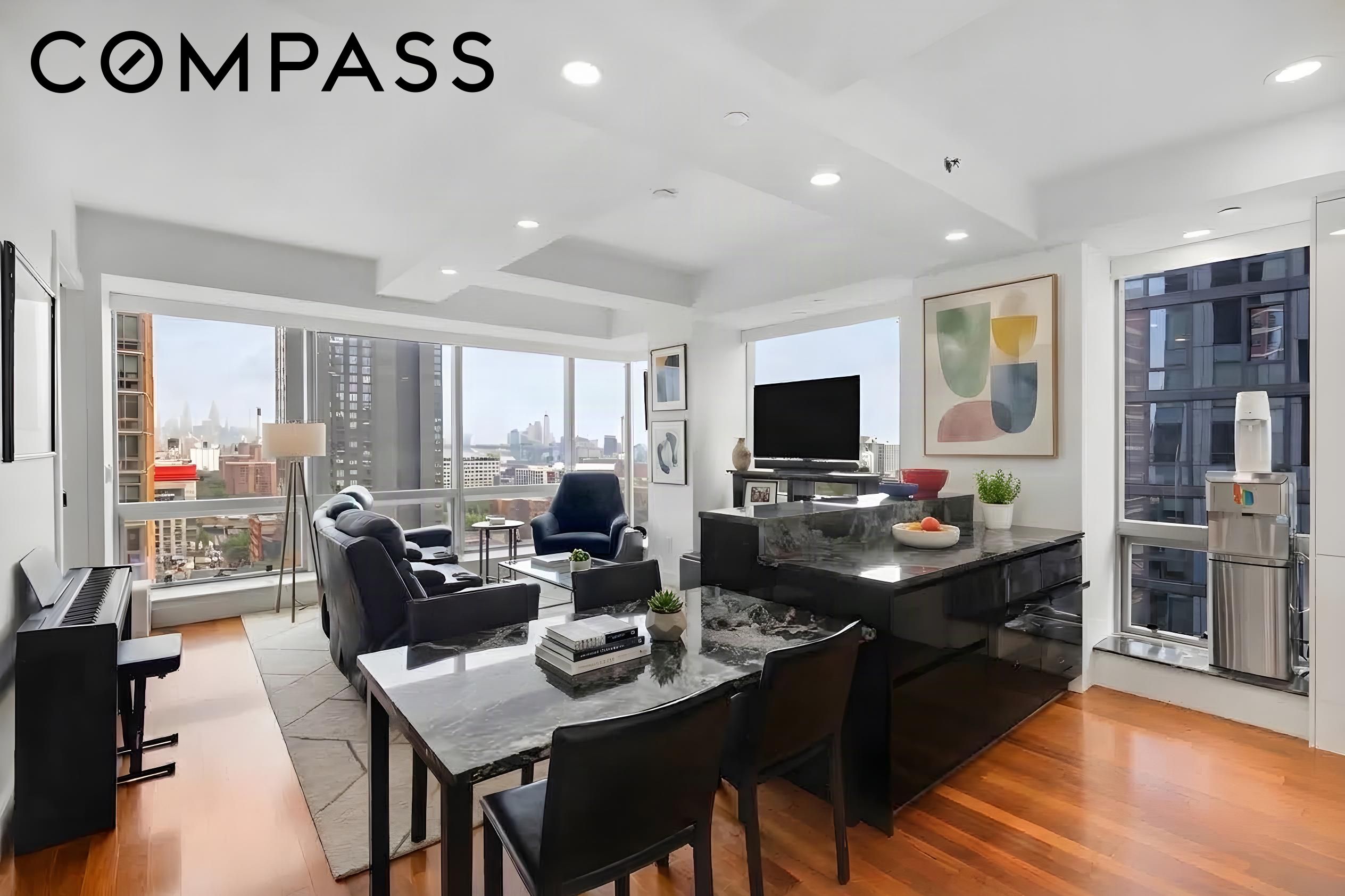 Furnished high-rise living and dining room with floor-to-ceiling windows overlooking the city.