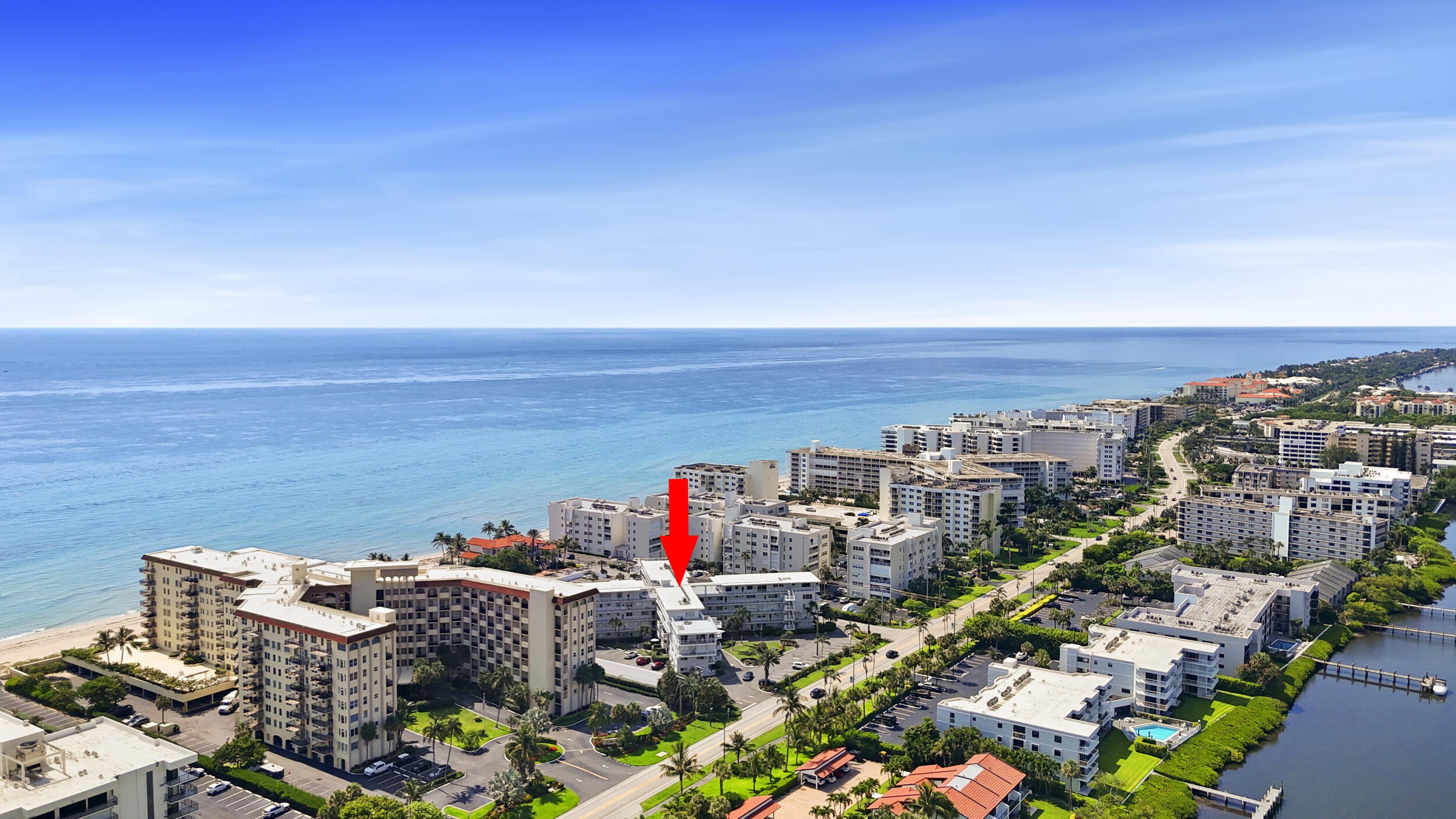 Aerial view of oceanfront condominiums, with a red arrow marking one building.