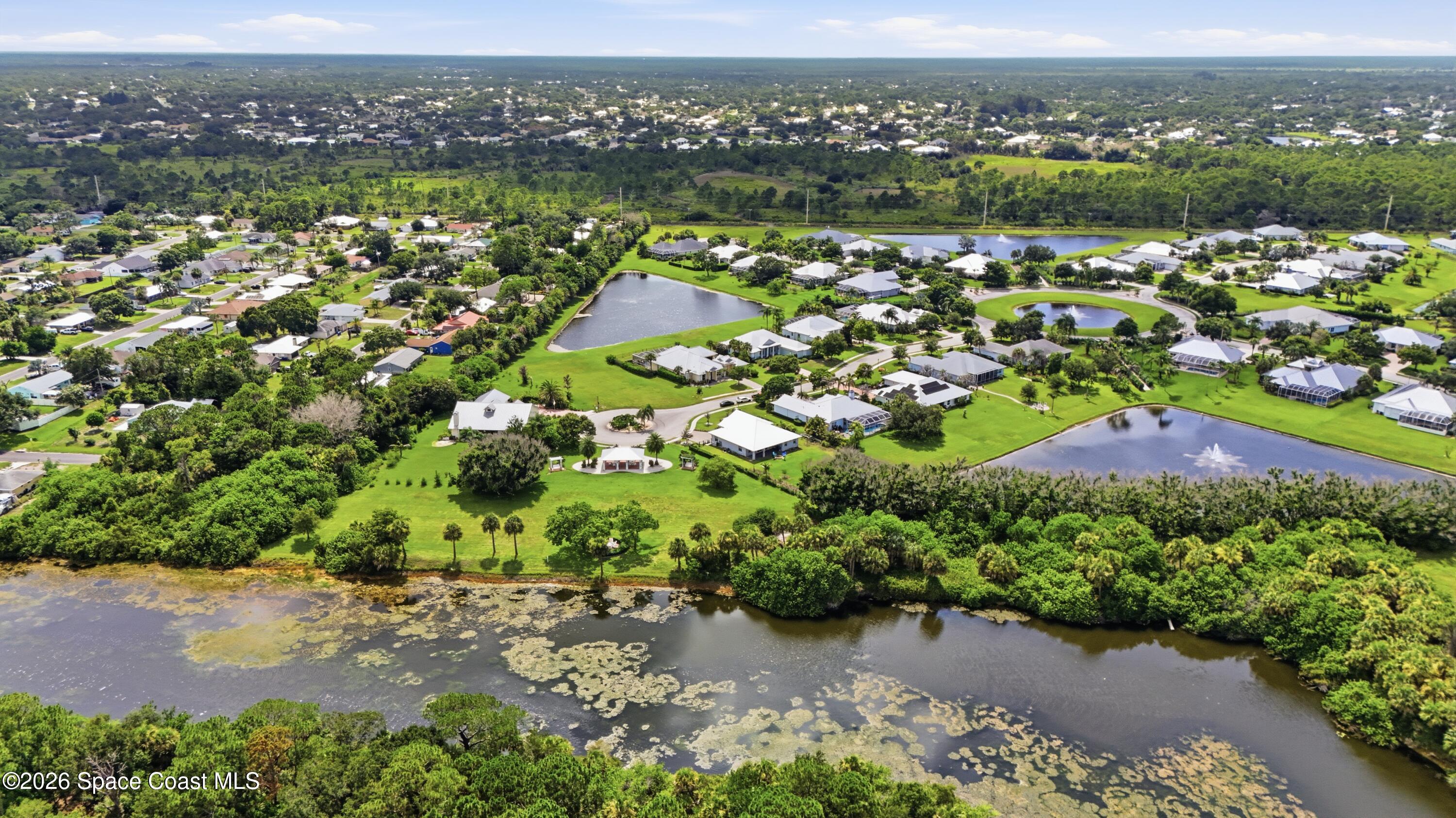 Aerial view of homes beside ponds and a broad marshy waterway.