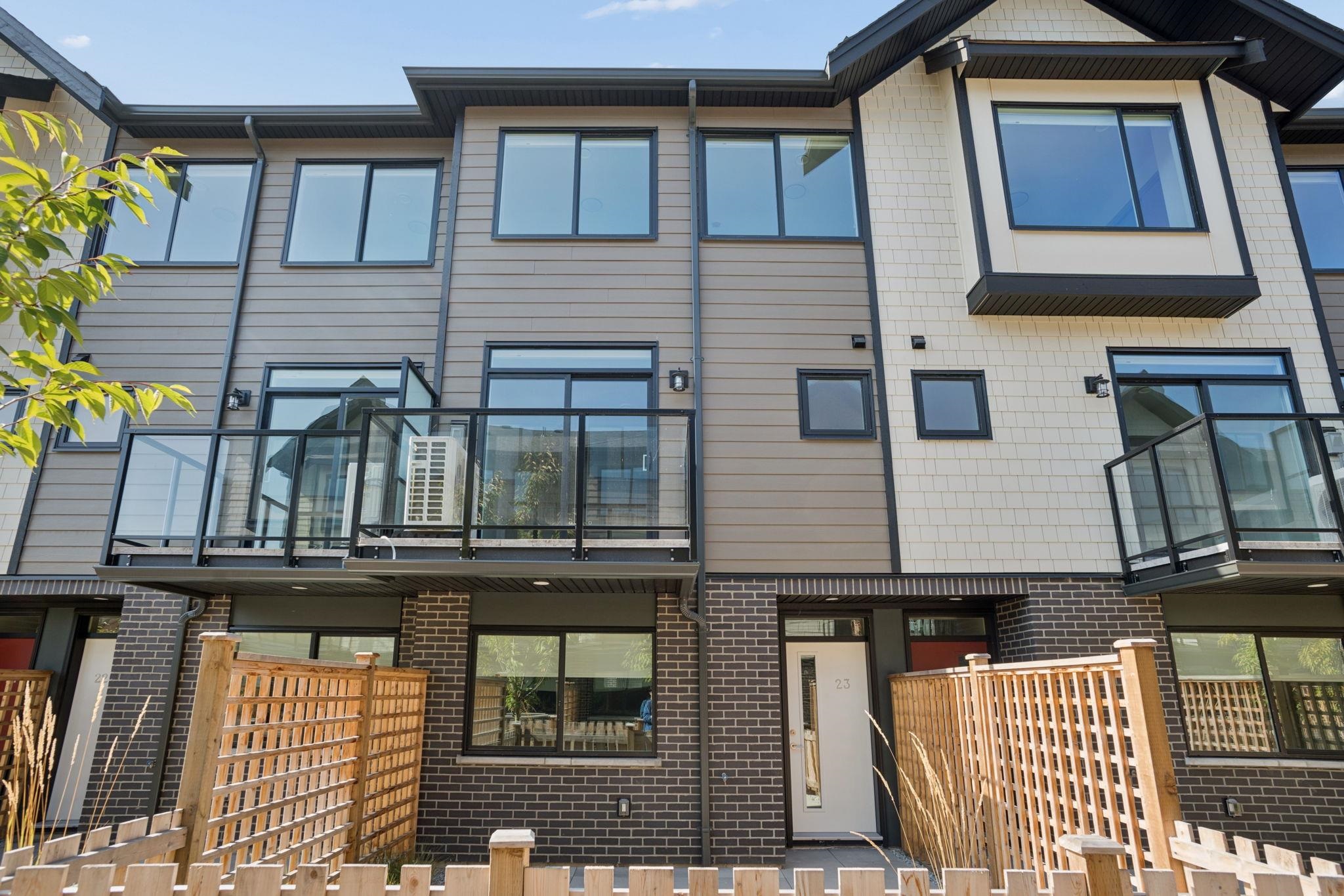 Attached townhouses with glass-railed balconies and fenced patios.