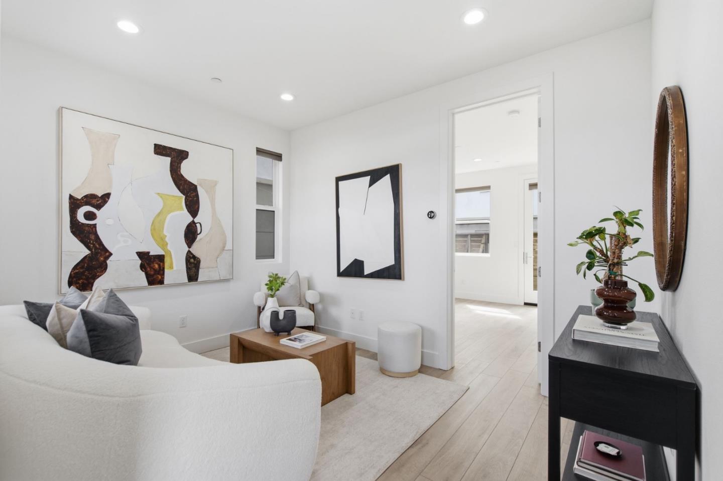 Staged living room with a white sofa, abstract artwork, and pale wood floors.