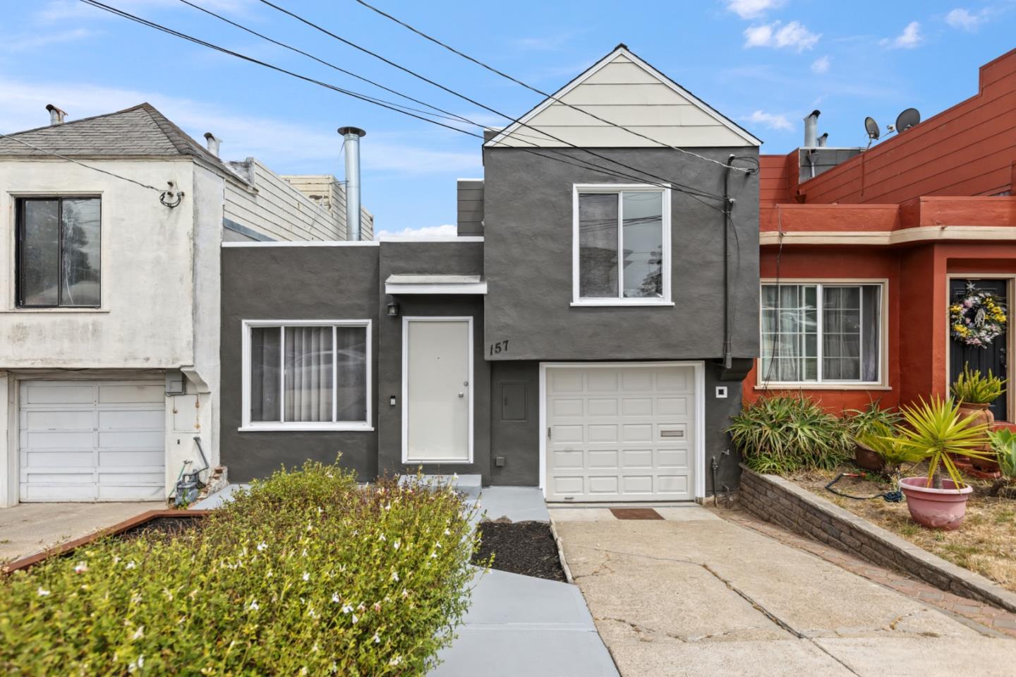 Gray two-story home with white trim, a peaked roof, and an attached garage.