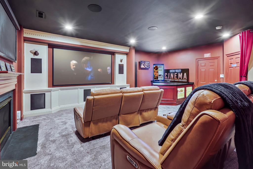 Home theater with a large projection screen and rows of tan leather recliners.