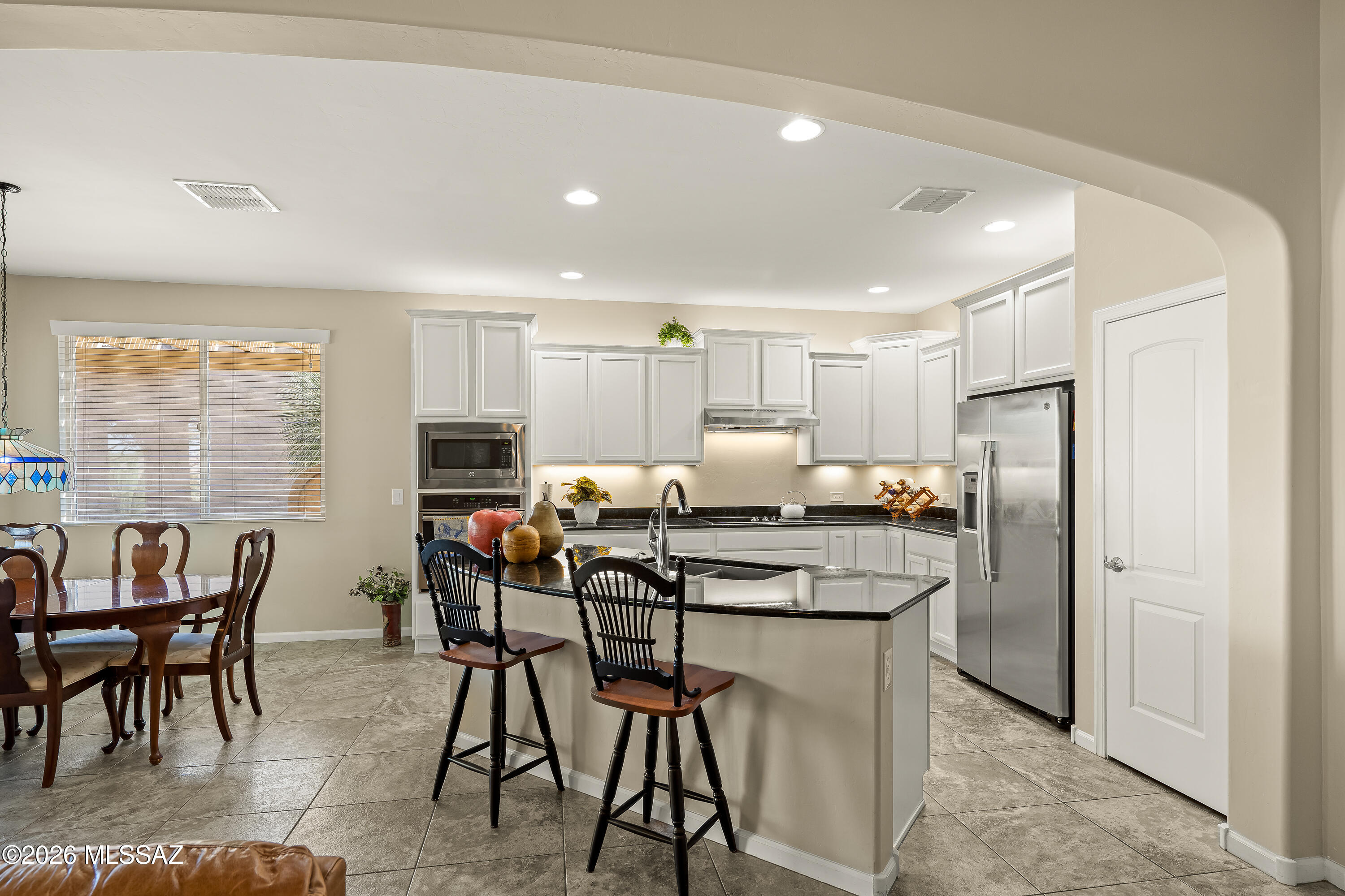 Kitchen with white cabinets, stainless appliances, a large island, and an adjoining dining area.