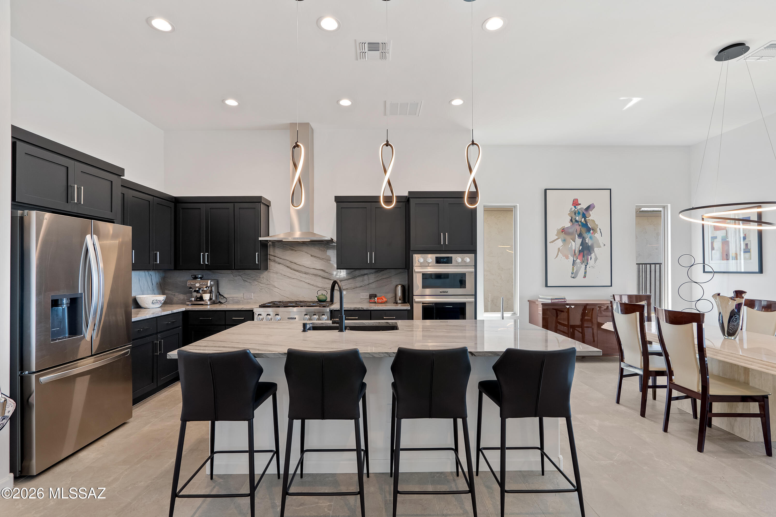 Modern kitchen with dark cabinets, stainless steel appliances, and a large island with four bar stools.