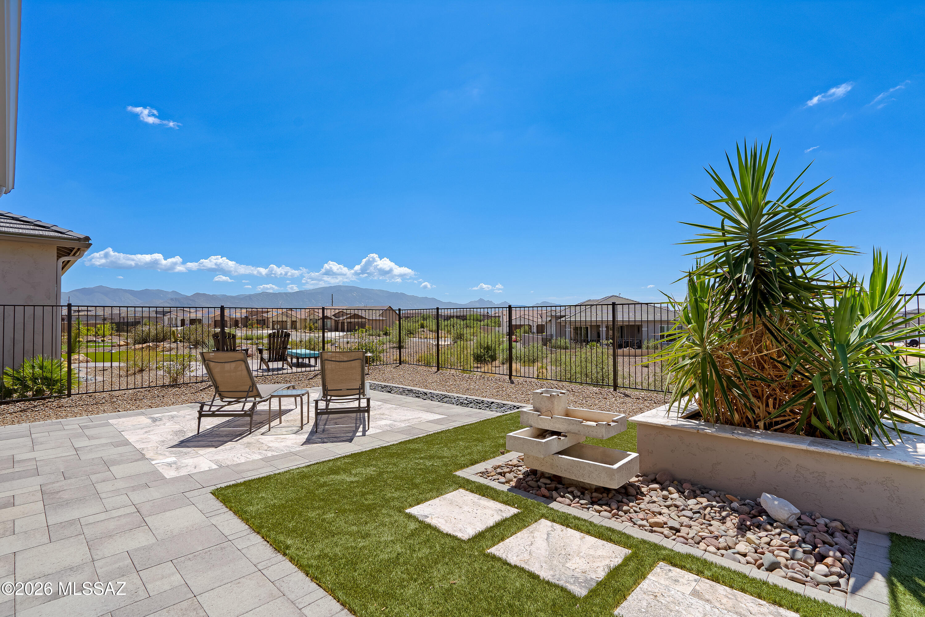 Backyard patio with lounge chairs, desert landscaping, and distant mountain views.