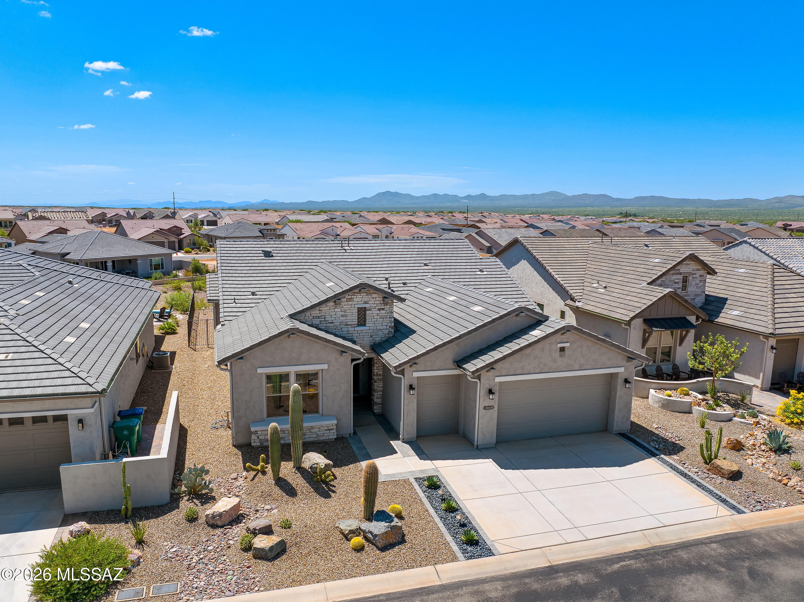Desert home with a stone-accented facade, cactus landscaping, and mountain views beyond the neighborhood.
