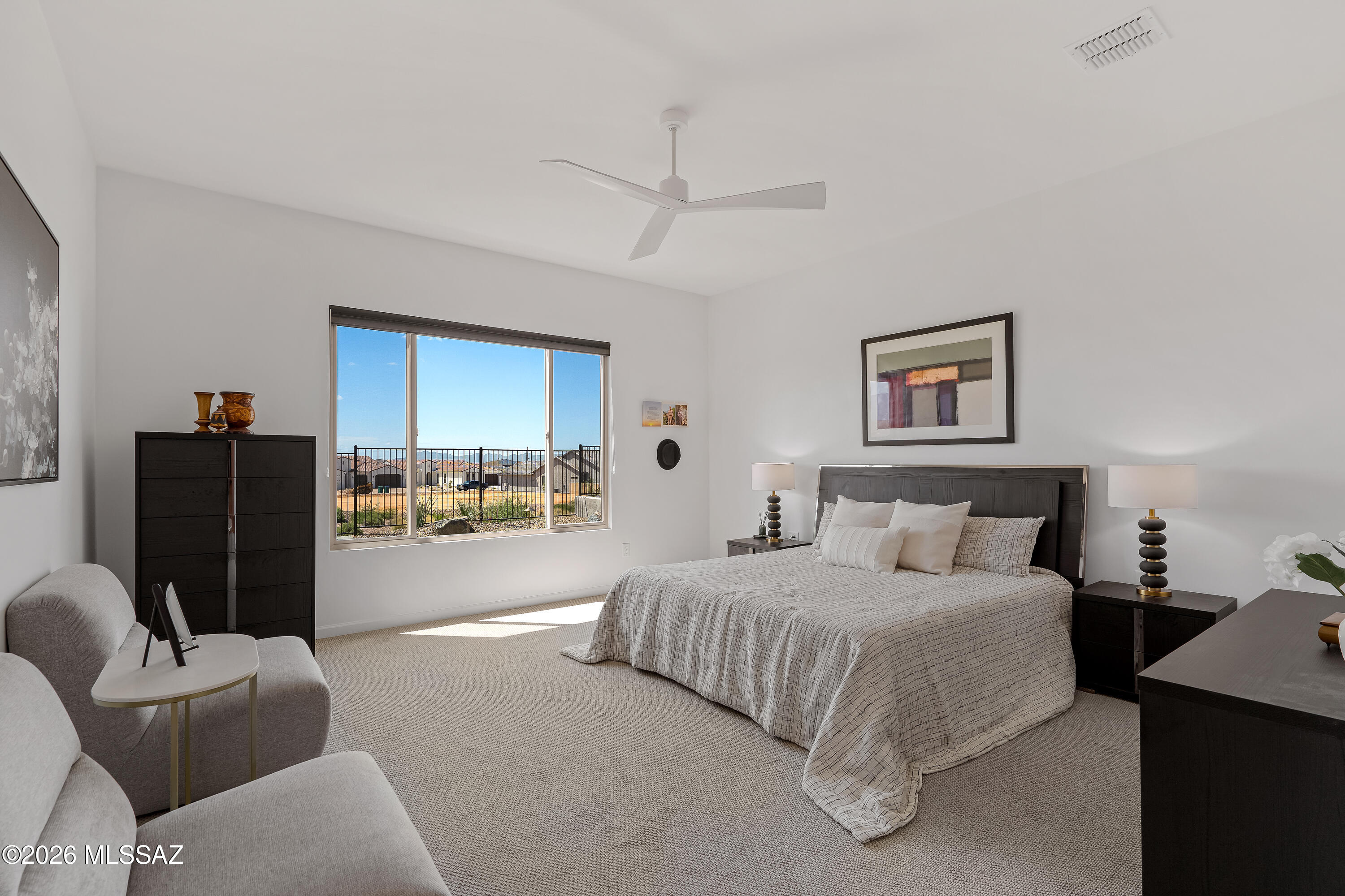 Furnished bedroom with a king-size bed and a large window overlooking distant mountains.