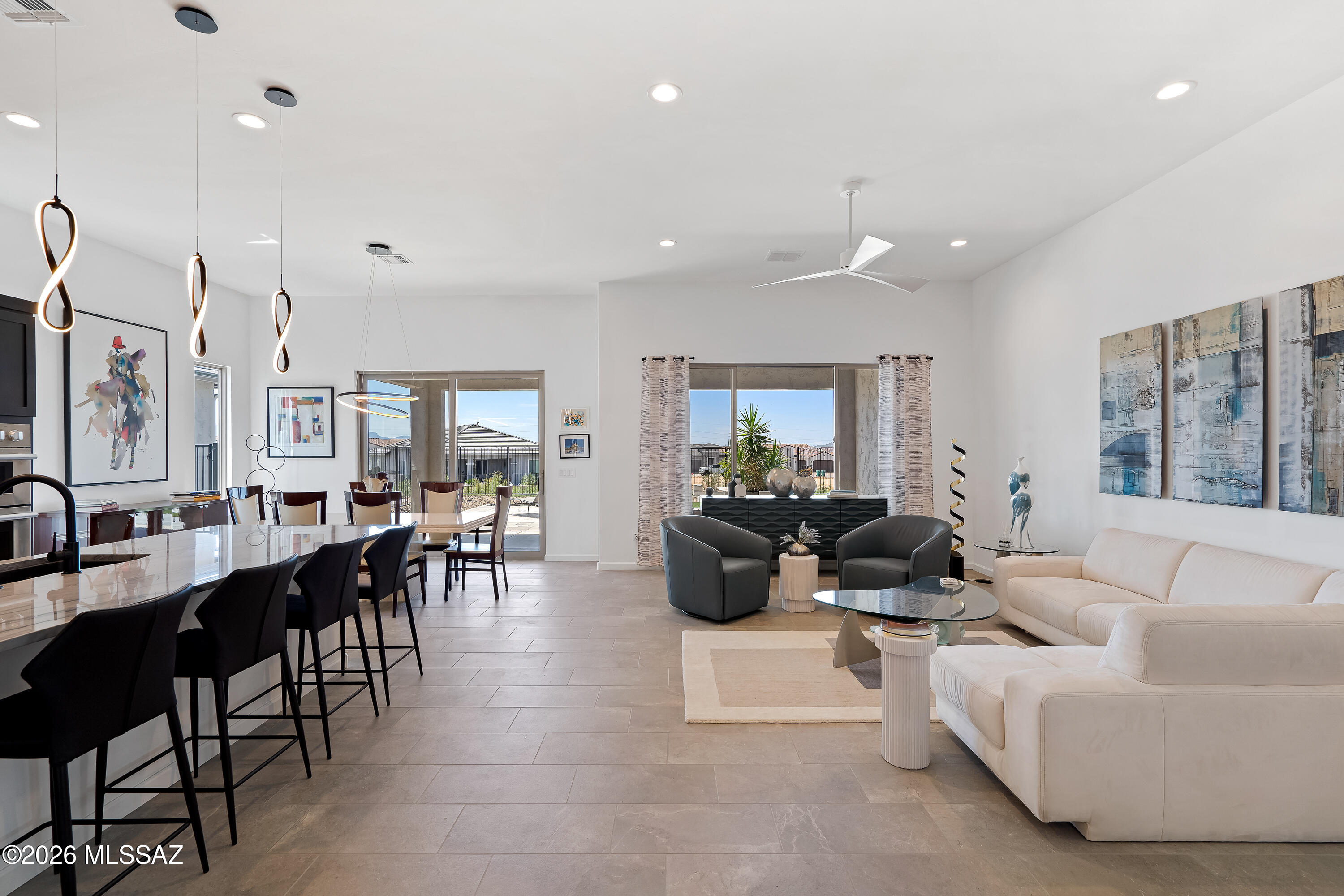 Open-plan living and dining room with a white sectional, black dining chairs, and backyard-facing glass doors.