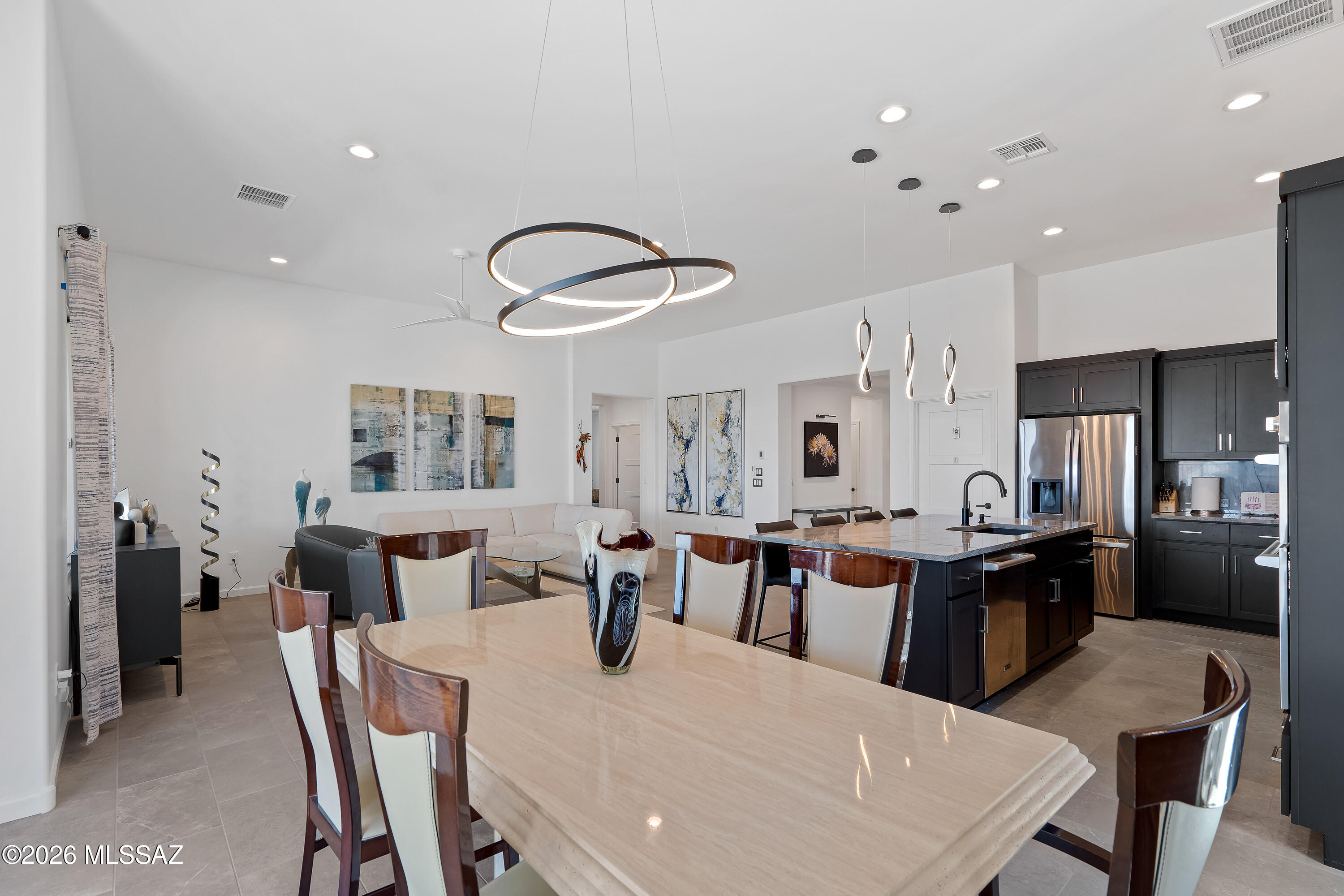 Dining area with a stone table opens to a modern kitchen and living room.