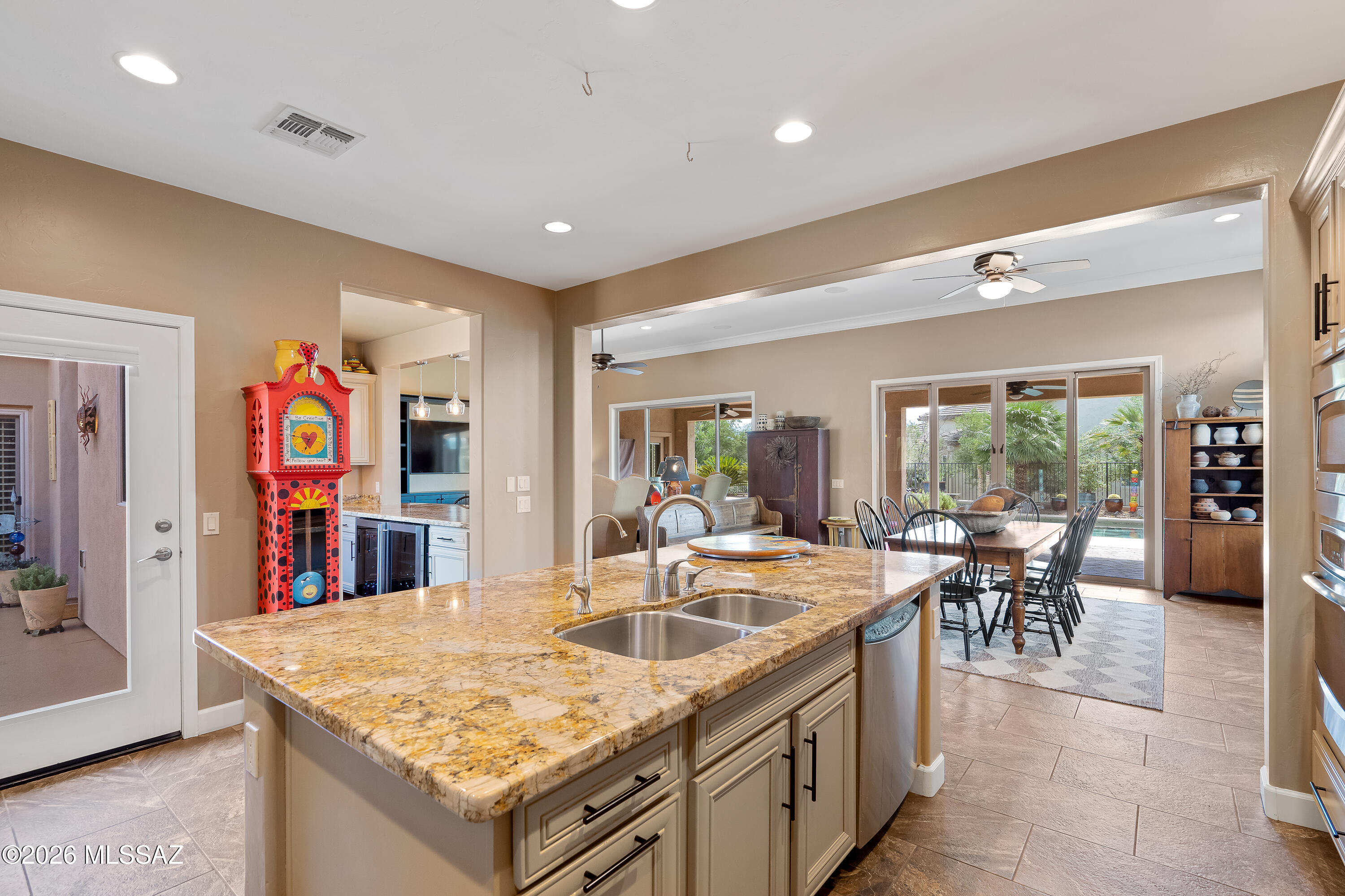 Kitchen with a granite island opening to a dining area and patio.