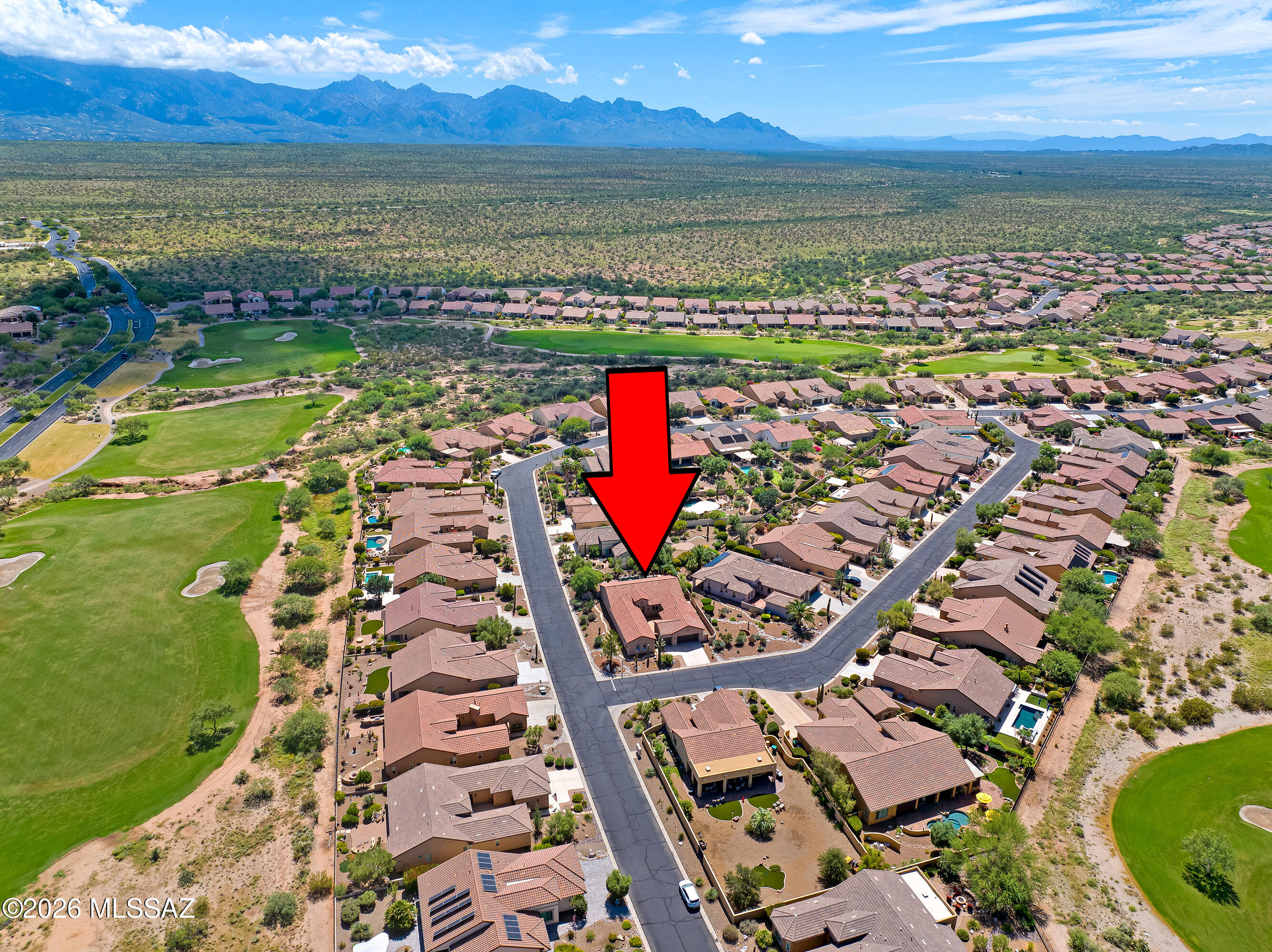 Aerial view of the marked home beside a golf course, with desert mountains beyond.