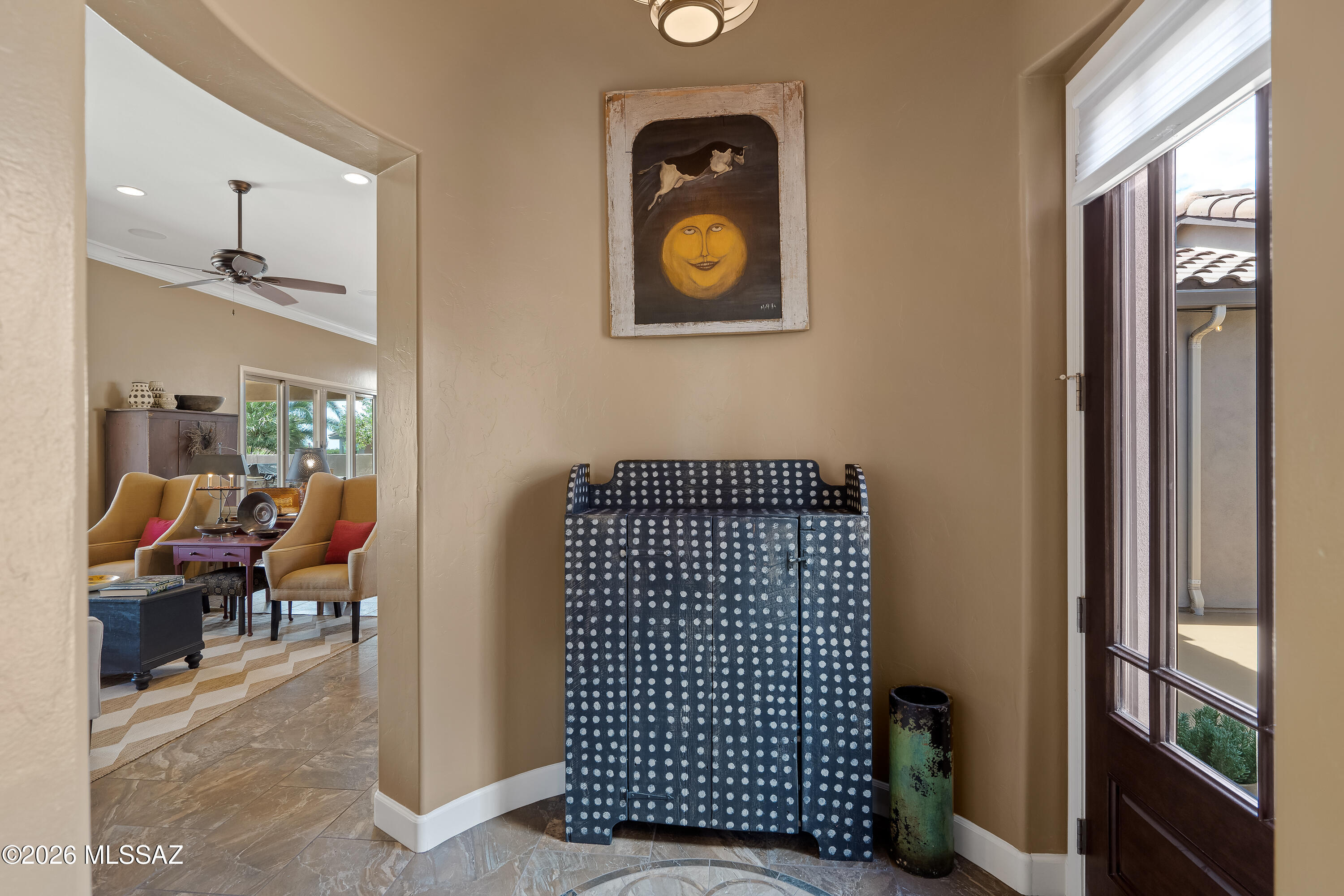 Furnished entryway with a dotted blue console cabinet, framed artwork, and glass-paneled front door.