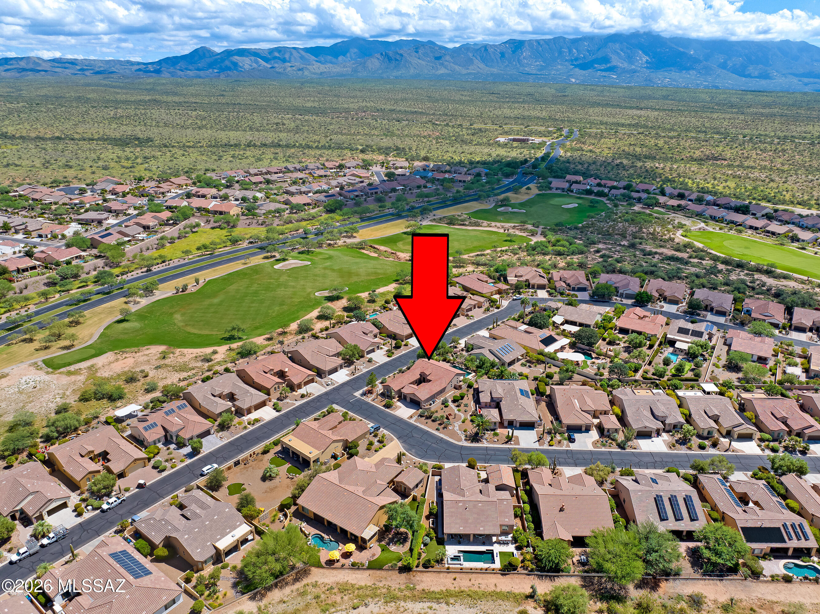 Aerial view of the marked home beside a golf course, with desert mountains beyond.