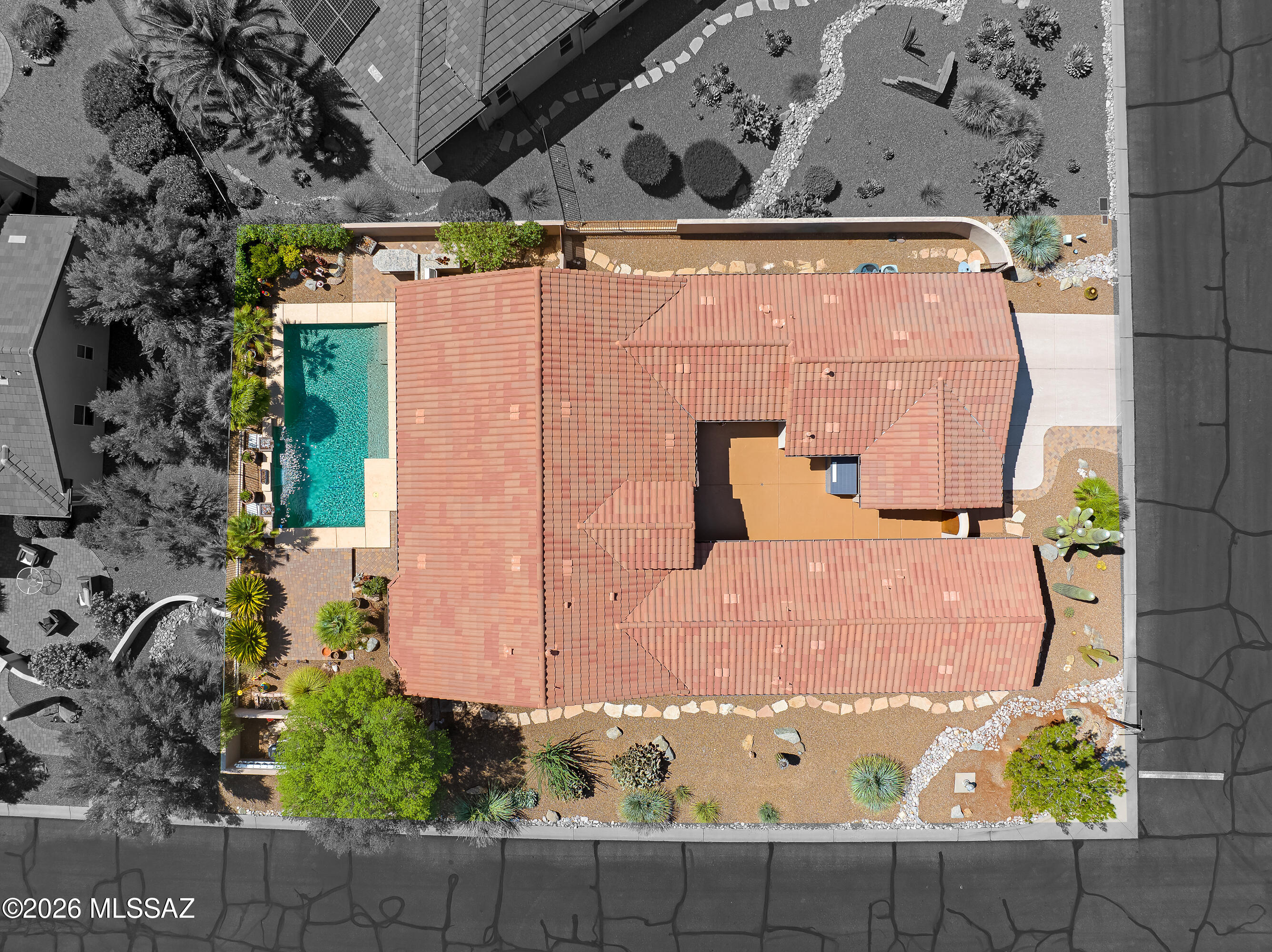 Aerial view of a tile-roofed home with a backyard pool and desert landscaping.
