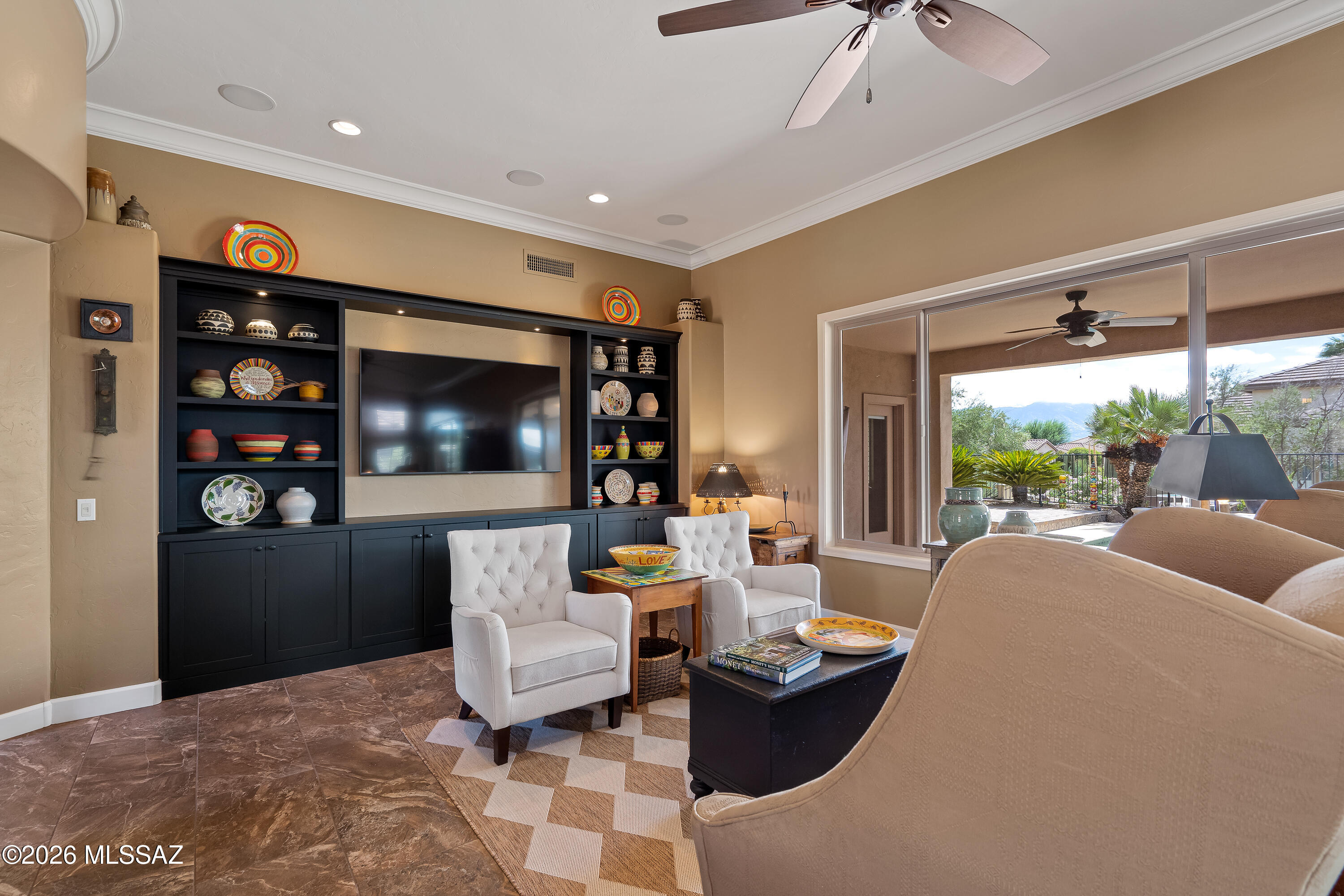 Living room with a built-in entertainment center, white armchairs, and patio doors framing mountain views.