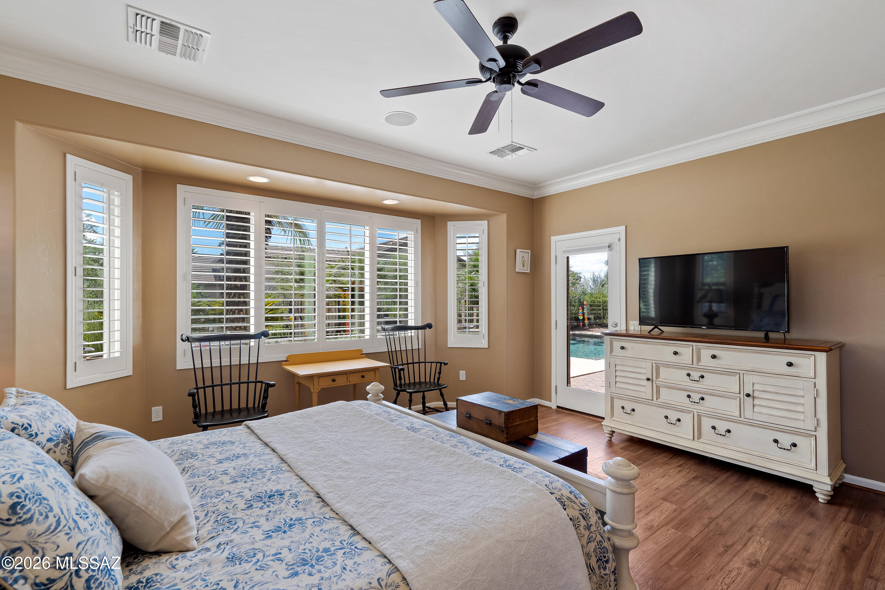 Bedroom with a blue-and-white bed, plantation shutters, and a view of the pool through the doorway.