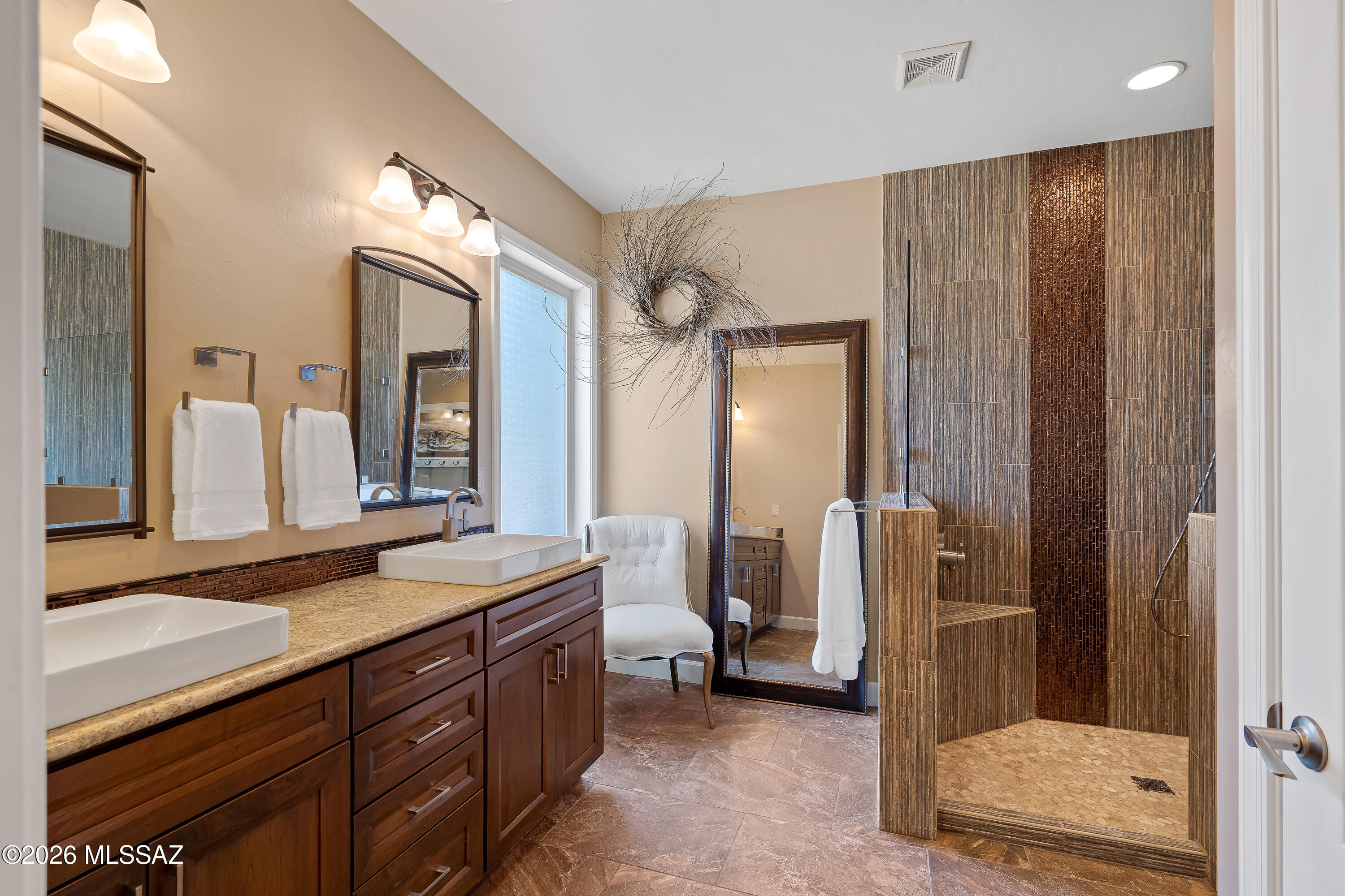 Bathroom with a dark wood double vanity and a walk-in shower with textured brown tile.
