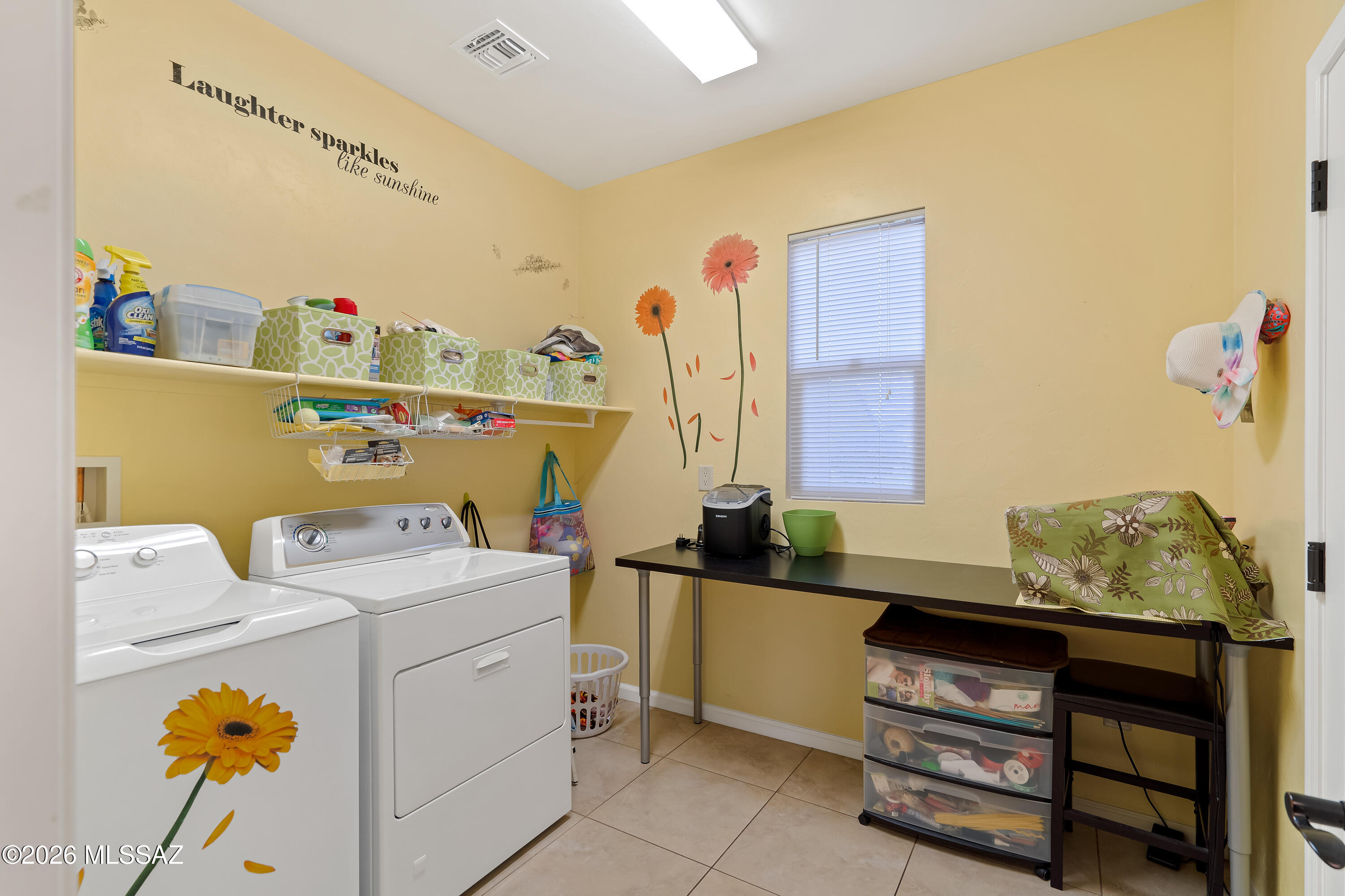 Laundry room with white washer and dryer, yellow walls, and wall-mounted storage shelves.